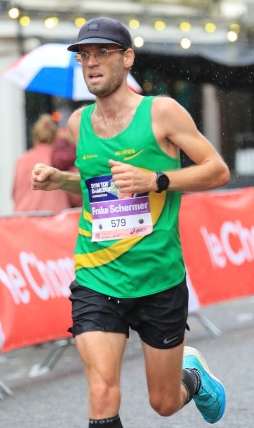 Frake racing in a green club vest, running through the rain during a road race